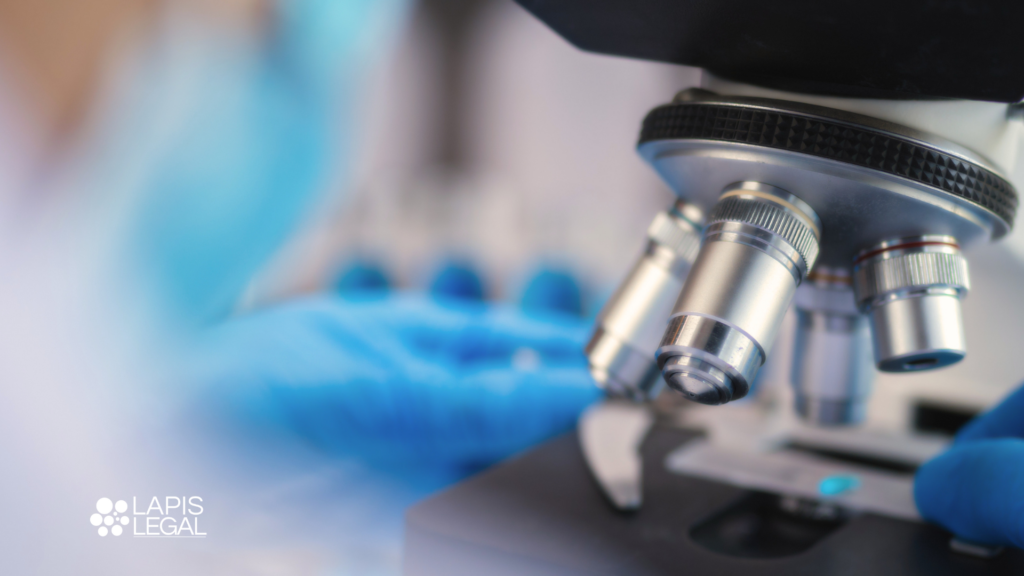 hand with blue glove working at a microscope